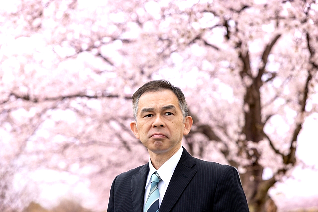 桜の木の下で険しい表情の男性